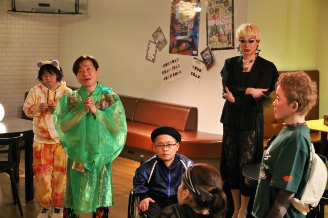映画の場面。部屋に集まった出演者たち