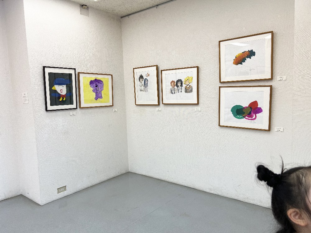 白い壁に間隔をあけて飾られた、額入りの絵の作品