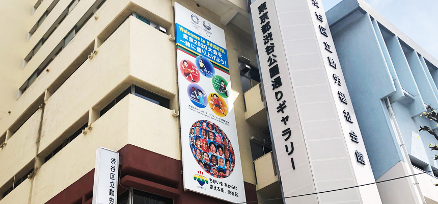 ビルの壁面に、たくさんの笑顔を描いた大きな垂れ幕がかかっている