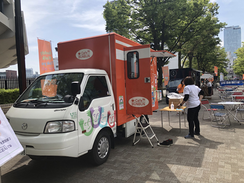 会場に停まっているオレンジ色のキッチンカーと、間隔をあけて置かれたテーブル