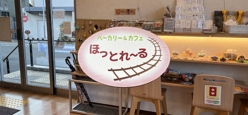 「ベーカリー&カフェ ほっとれ~る」の看板と、作業所の小物が並ぶ店内の棚
