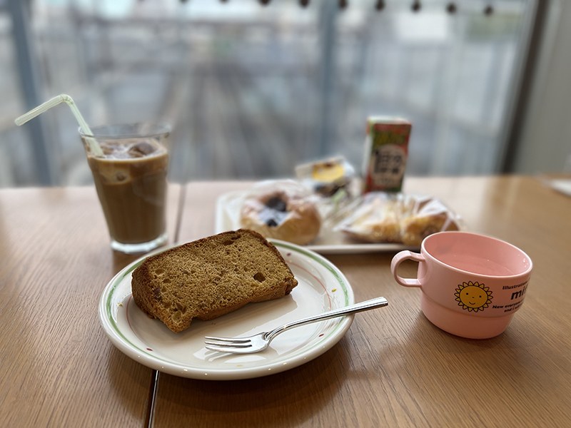 パウンドケーキとパン、グラスの冷たい飲み物、ピンクのカップが並ぶテーブル