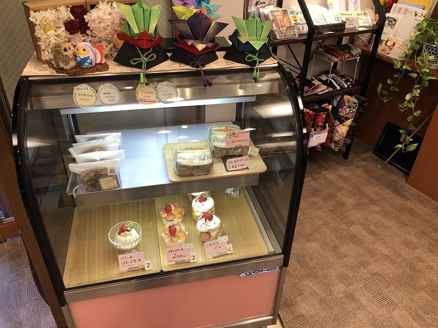 ケーキが並ぶショーケースと、その上に飾られた手作りの作品