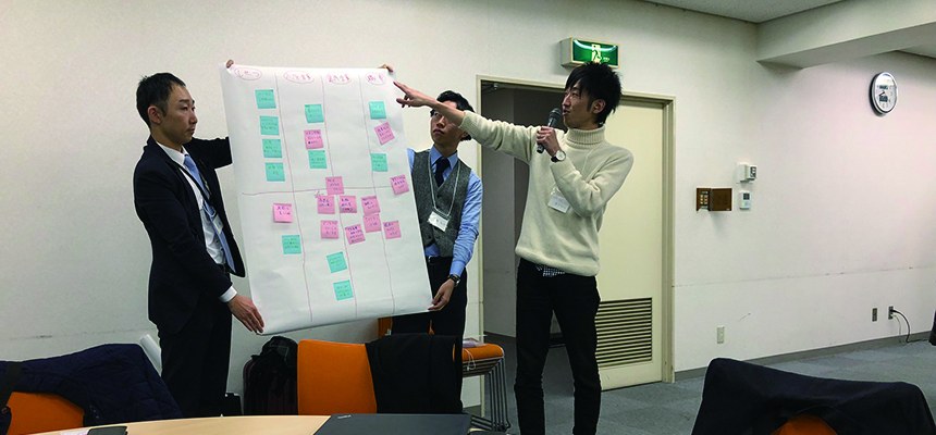 付せんを貼った模造紙を掲げて発表する参加者