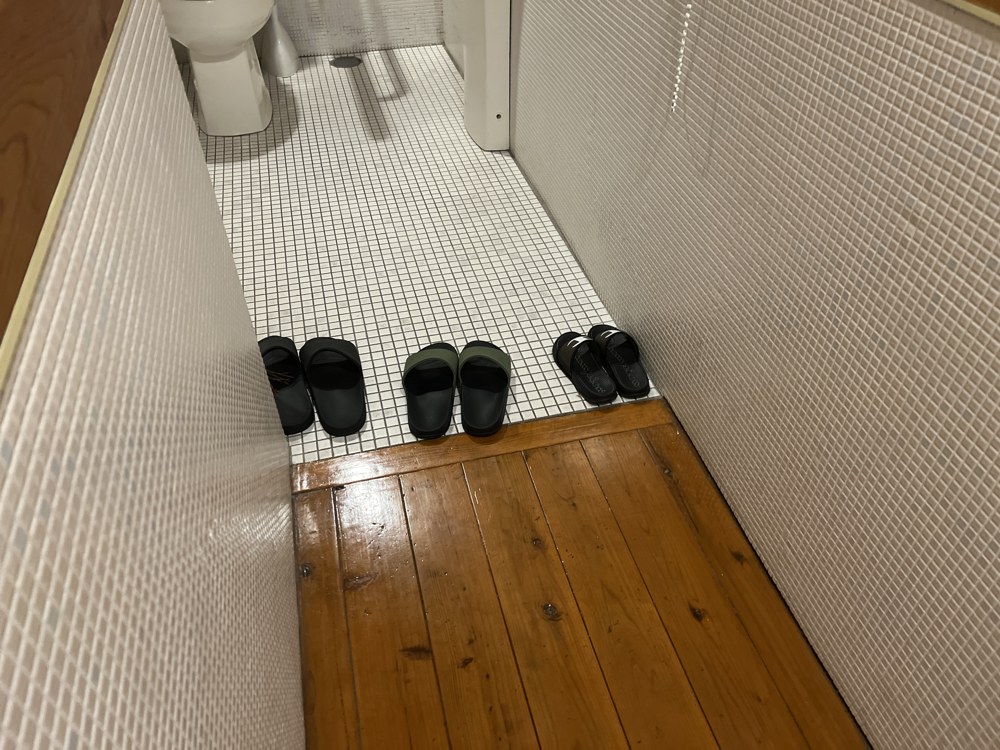 トイレの入口の床。タイルの床との間は木の床になっていて、スリッパが並んでいる