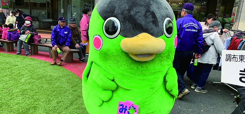 黄緑色の鳥の着ぐるみのゆるキャラと、にぎわう会場の広場