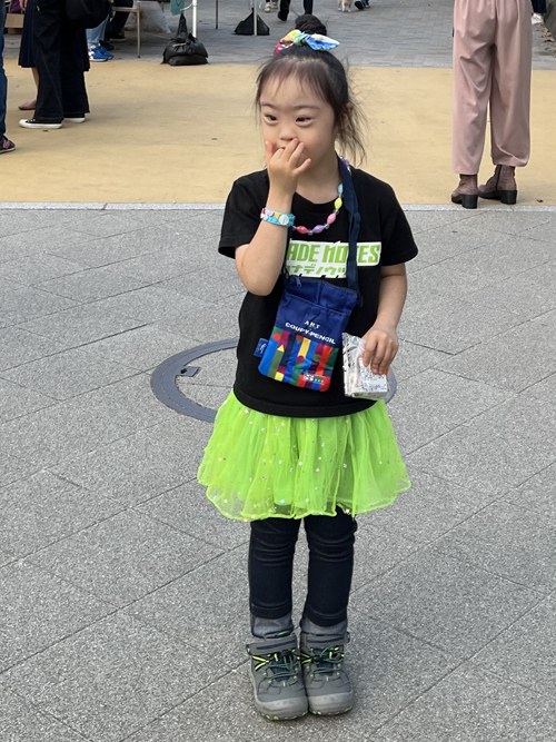 黒いTシャツにネオンイエローのチュチュを着て、路上に立つ娘