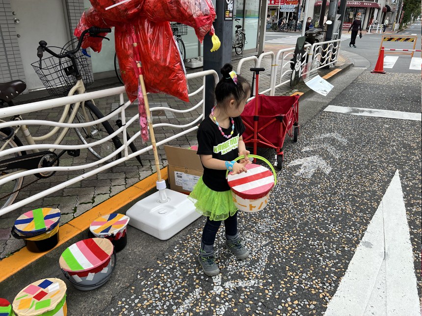 できあがったガムテープ太鼓を持って、歩行者天国の道路に立つ娘