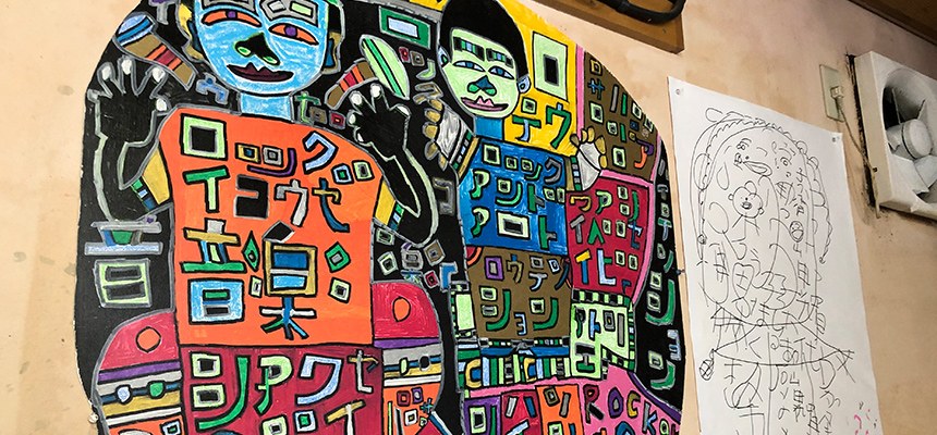 カタカナの文字でうめつくされた、2人の人物を描いたカラフルな絵