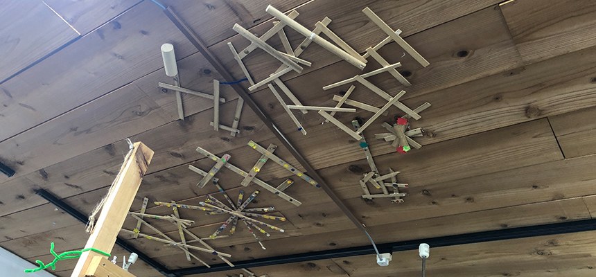 木の棒を組み合わせた作品が吊るされたロウテンションの天井