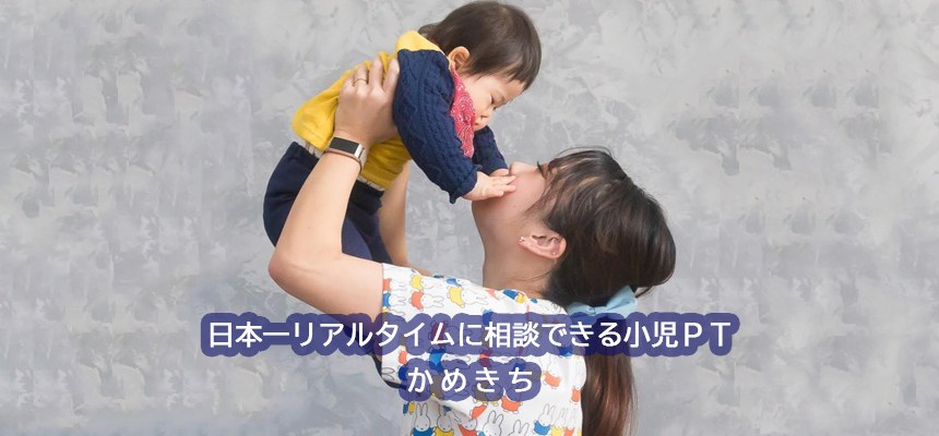 子どもを高く抱き上げてほほえむかめきち先生。「日本一リアルタイムに相談できる小児ＰＴ かめきち」の文字