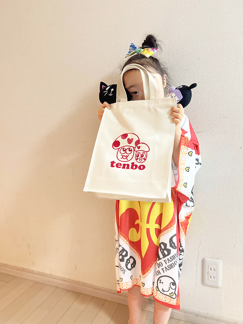 大きなTシャツを着て、トートバッグを胸に抱えている子ども