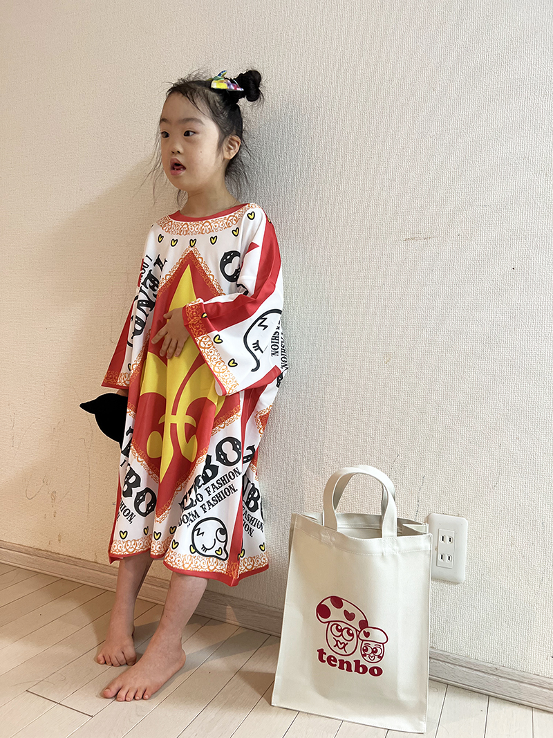大きなTシャツを着て、壁の前でポーズをとる子ども