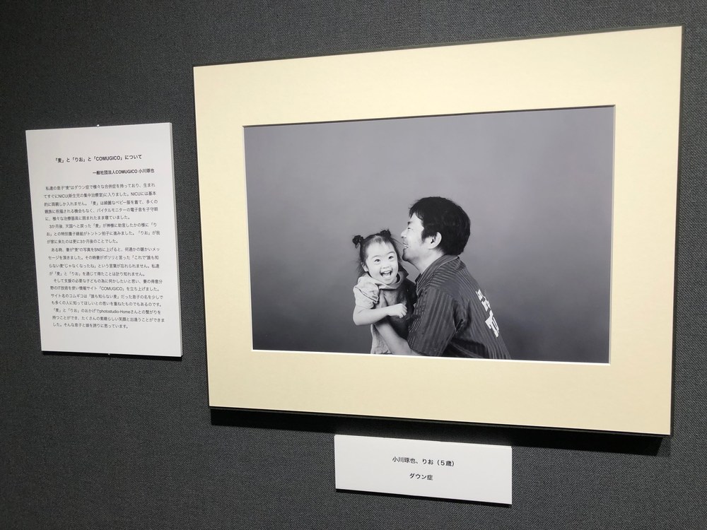 ギャラリーの壁に展示された、父と娘が笑い合うモノクロ写真とキャプション