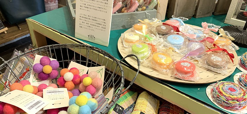 カラフルなフェルトボールや丸いコースターなどの雑貨が並ぶ台