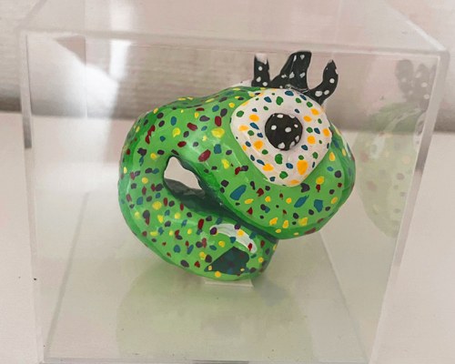 透明なケースに入った、緑に水玉模様の立体作品「コムギコ像」