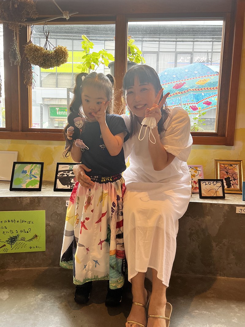 窓辺で寄りそって写る、子どもと白いワンピースの女性