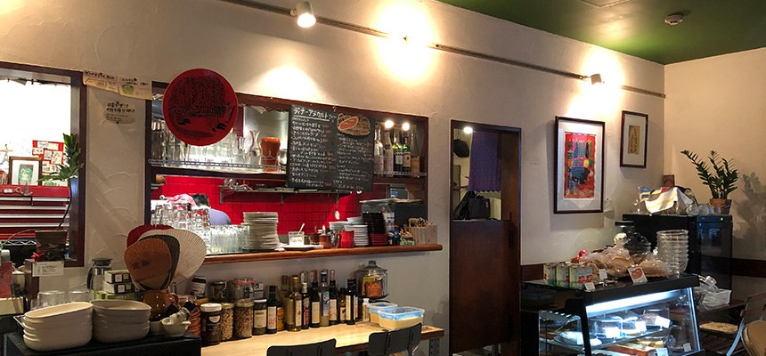 ニルカフェの店内。カウンターの奥に黒板のメニューや食器の棚が並んでいる