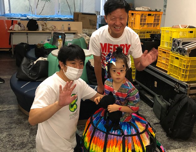 MERRY SMILE SHIBUYA2020の会場で、虹色のドレスを着た娘と手を振る男性2人