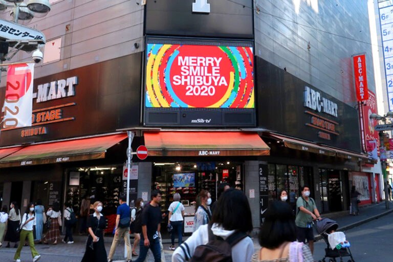 商店街のビルの上のビジョンに映る「MERRY SMILE SHIBUYA 2020」のロゴ