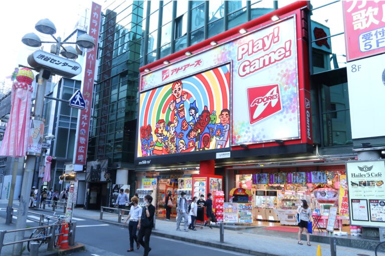 ゲームセンターのビルの大型ビジョンに映る、笑顔の人々のイラスト