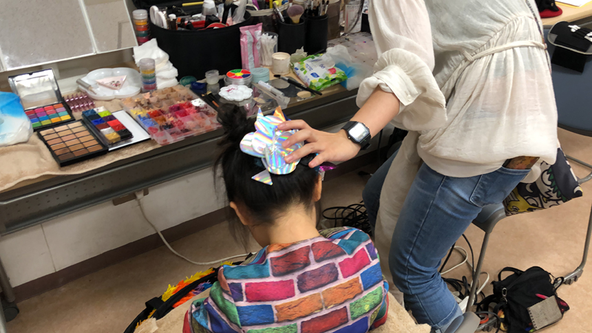 鏡の前で、子どものメイクをしているメイクさん