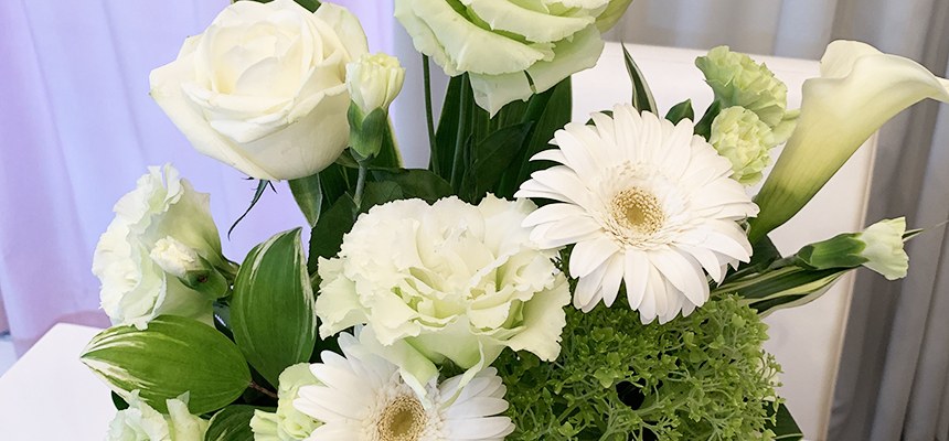 白いバラやガーベラ、カラーなどを束ねた白と緑の花束