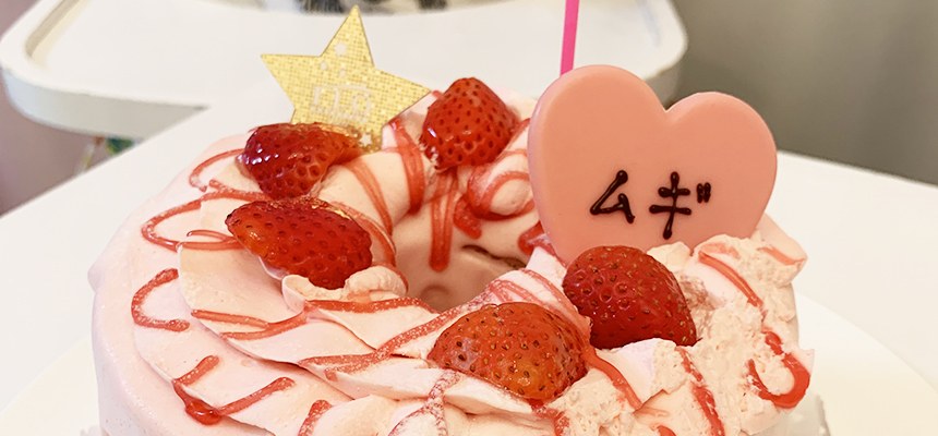 イチゴと「ムギ」と書かれたハートのプレートをのせたピンクのケーキ