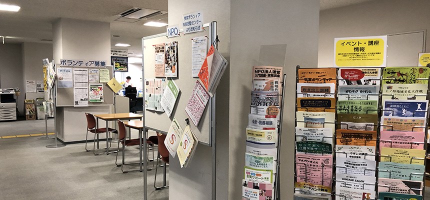 市民活動支援センターの中。ボランティア募集やイベント・講座のチラシがずらりと並ぶラック